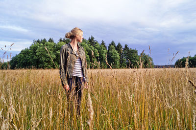 Man standing on field against cloudy sky
