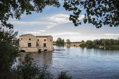 Buildings by river against sky