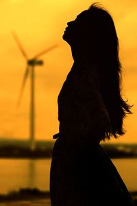 Side view of silhouette woman standing against sky during sunset