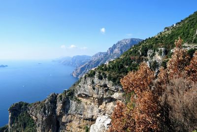 Scenic view of sea and mountains against clear blue sky