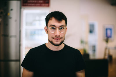 Portrait of young man standing at home