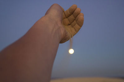 Close-up of hand against sky at sunset