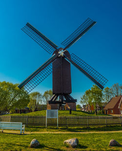 Traditional windmill on field against clear blue sky