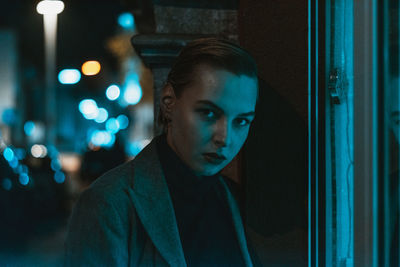 Portrait of young woman standing on sidewalk at night