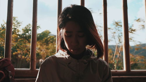 Portrait of beautiful young woman standing against window