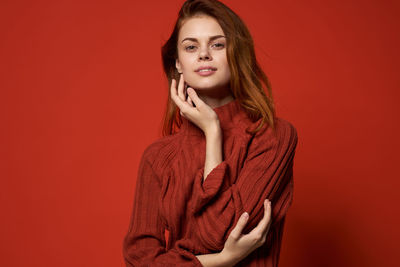 Portrait of beautiful young woman against red background