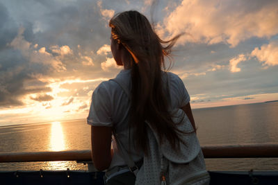 Beautiful woman at beach against sky during sunset