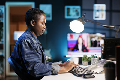 Side view of man using laptop at office