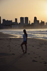 Full length of woman on beach against sky during sunset