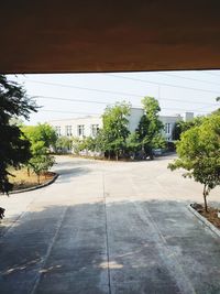 Road by trees and buildings against sky