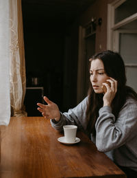 Young woman sitting on table at home