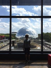 Full length of boy standing against glass window in city