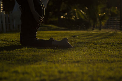 Low section of person kneeling on grassy field at park