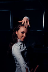 Portrait of woman standing against dark room