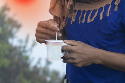 Midsection of man holding coffee cup