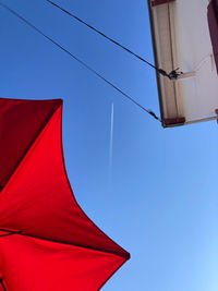 Low angle view of flag against buildings against clear blue sky