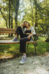 Portrait of woman sitting on bench in park