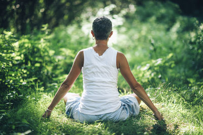 Rear view of man sitting on rock