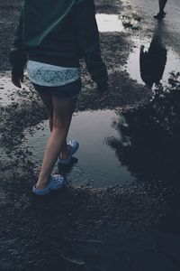 Low section of woman standing on puddle at beach