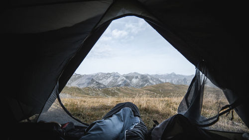 Low section of person in tent against mountains