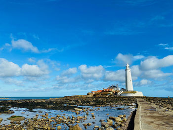 Lighthouse by sea against sky