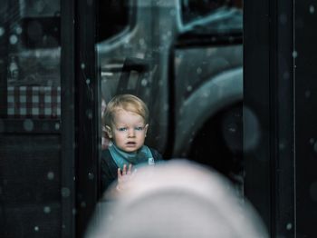 Portrait of boy looking through glass window