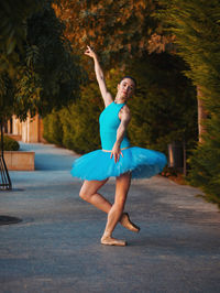 Ballet dancer dancing on footpath against trees