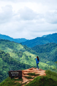 Rear view image of female traveler looking at a beautiful green mountains view
