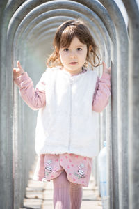 Portrait of cute girl standing against wall