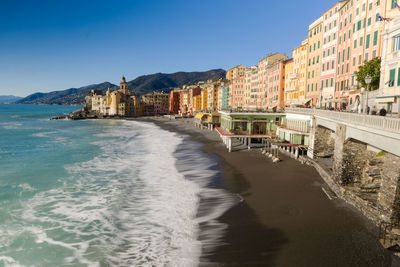 High angle view of beach by buildings against clear blue sky