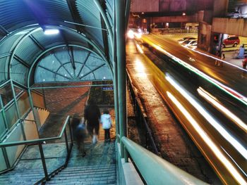 Light trails on road with people walking at steps during night