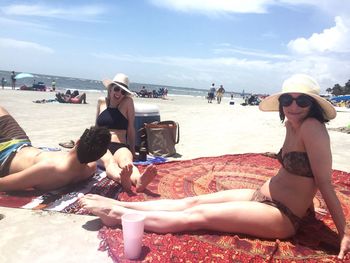 Young woman sitting on beach against sky