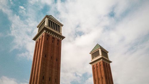 Low angle view of historic towers against cloudy sky