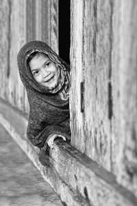 Smiling girl peeping from wood