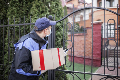 Mailman standing with box at gate