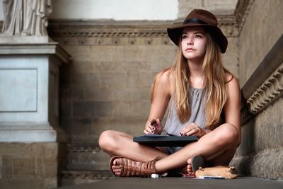 Young woman wearing hat sitting in building