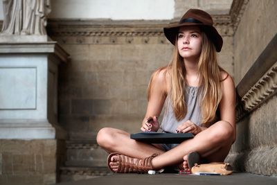 Portrait of young woman sitting on wall