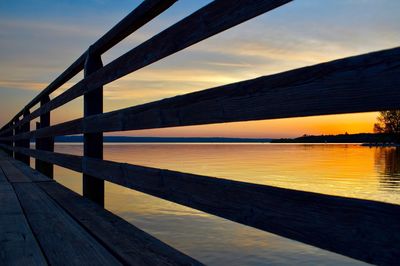 Pier over lake against sky during sunset