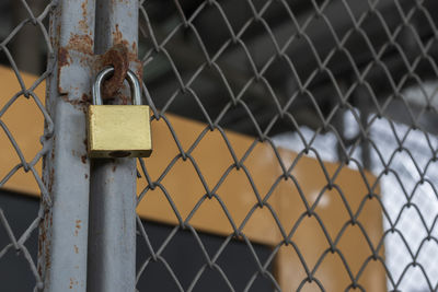 Brass padlock was locked with wire mesh door and blurred electricity power machine background