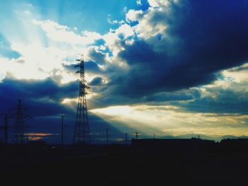 Low angle view of electricity pylon against cloudy sky