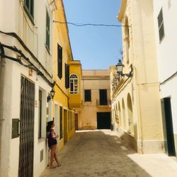 Woman walking on street amidst buildings in city