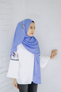 Portrait of woman standing against wall