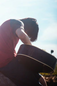 Side view of woman sitting against sky