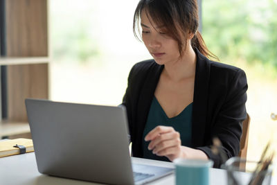 Midsection of woman using mobile phone while sitting on table