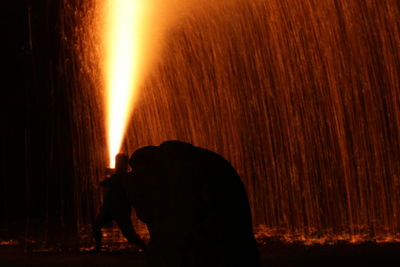 Silhouette man against orange sky at night