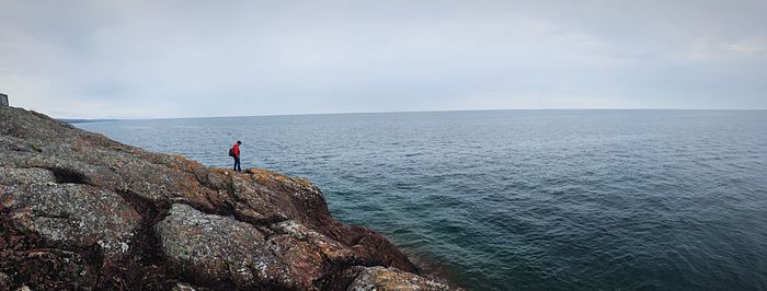 Man standing on rock formation against sea