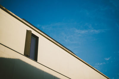 Low angle view of building window against blue sky on sunny day