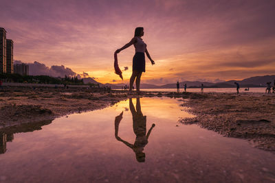 Man standing on beach against sky during sunset