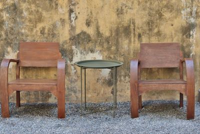 Empty chairs and table against wall in old house