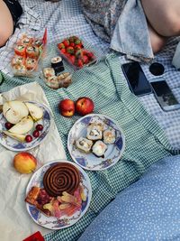 High angle view of hand holding fruit on table picnic on grass with flowers